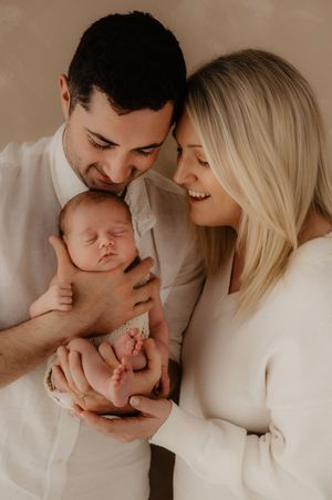 Family portrait series showing loving moments with sleeping newborn in neutral tones.