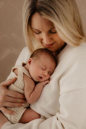 Peaceful moment between parent and sleeping newborn captured in warm neutral tones.