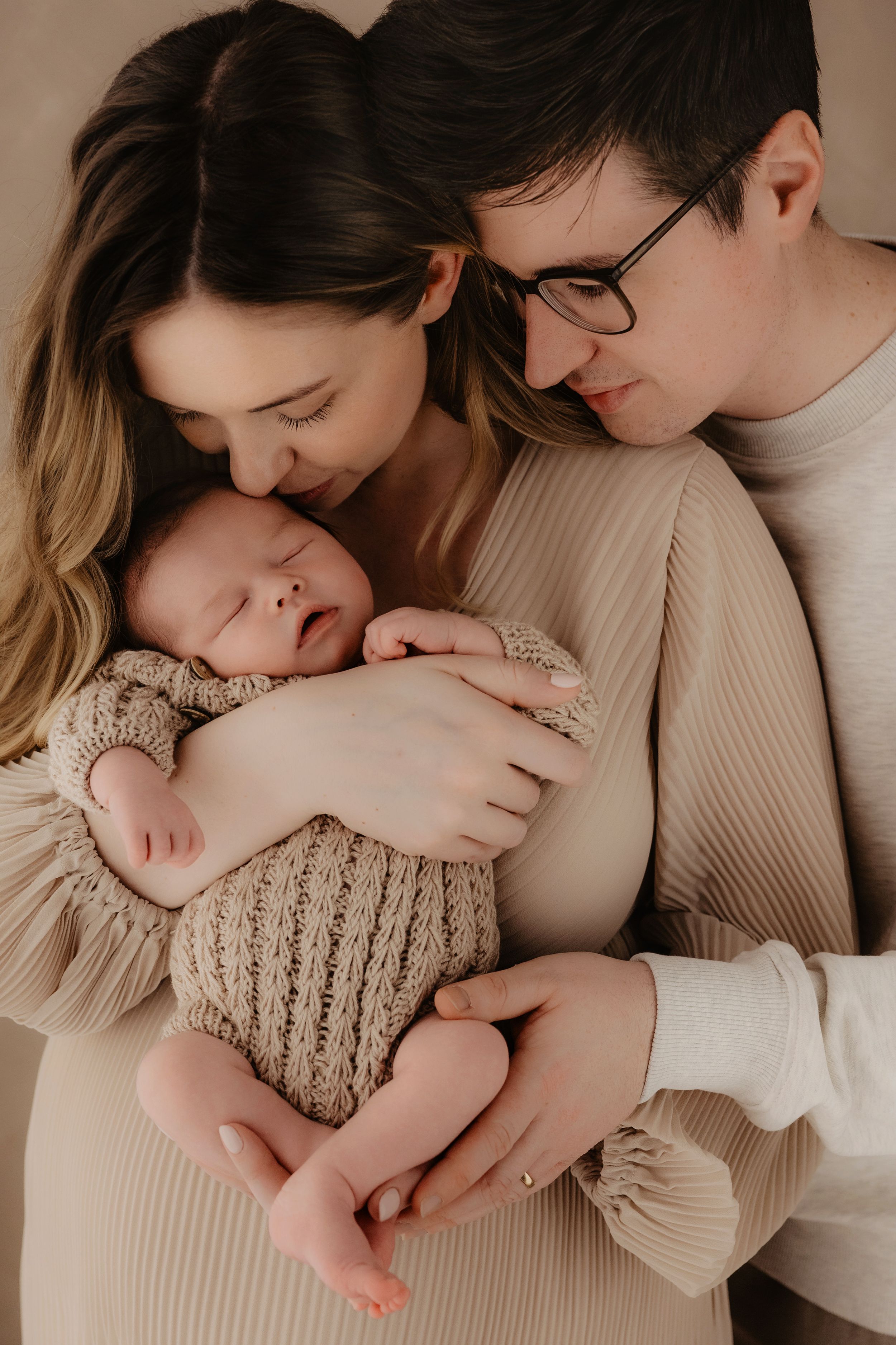 A series of intimate photos showing tender moments between a couple and their newborn baby in soft beige tones.