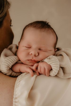 Peaceful sleeping newborn baby wrapped in beige knit blanket.
