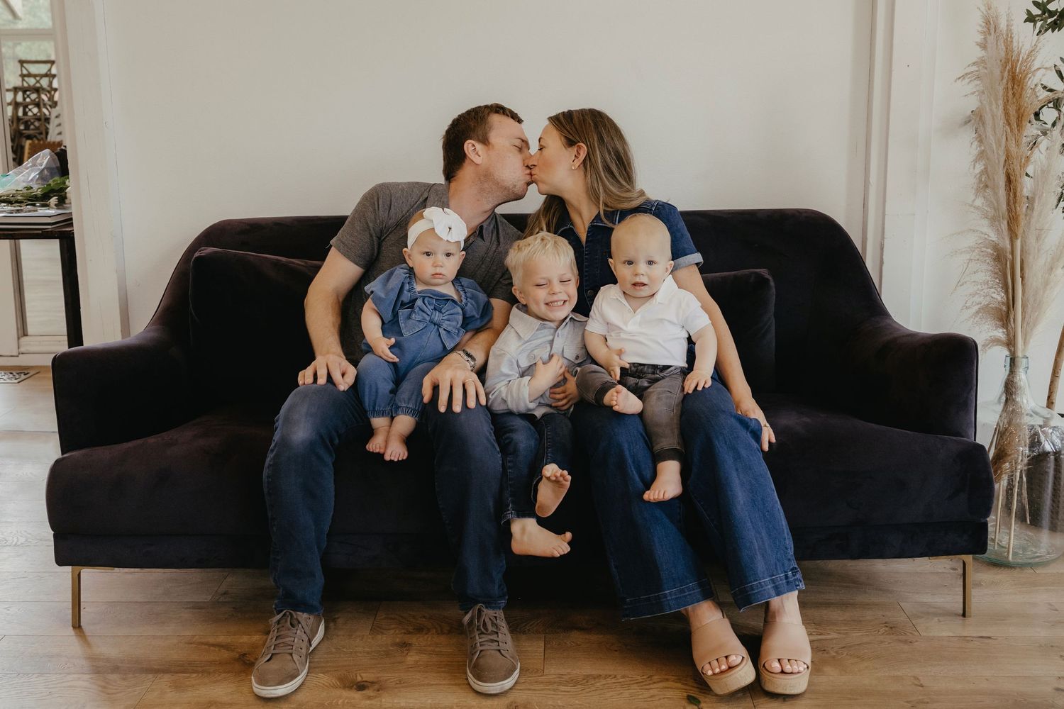 Intimate family moment on dark velvet couch with small children.