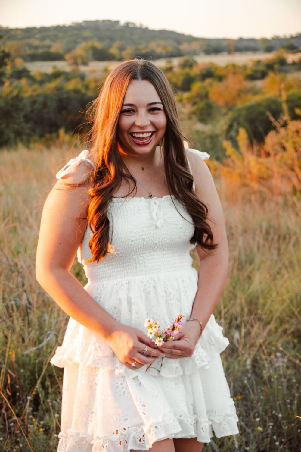 High school senior girl posing in a field during a senior portrait session in Boerne, Texas
