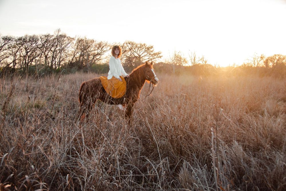 Woman horseback riding through a sunlit field in the Texas Hill Country