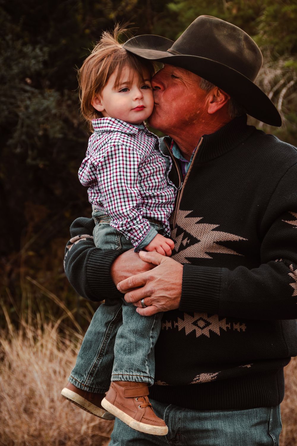 Father kissing his young son during a family portrait session in the Texas Hill Country