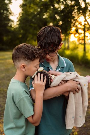 A child in a mint green shirt shares a tender moment with a caregiver against a golden sunset backdrop.