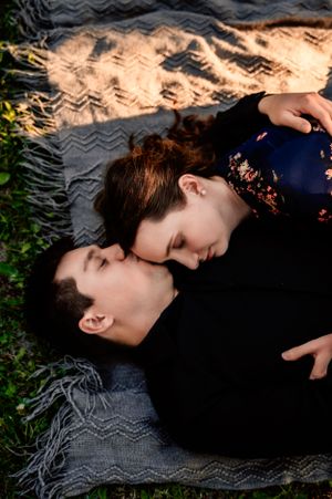 Romantic couple lying on textured blanket during sunset photo session.