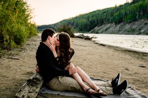 Romantic riverside portrait at sunset with mountains in background.