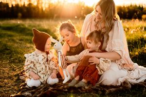 Family sits together in a golden meadow at sunset sharing tender moments in warm light.