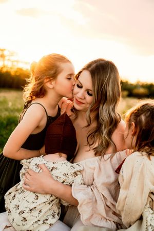 A tender family moment shared between a parent and children during golden hour in a sun-kissed field.
