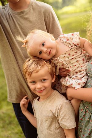 A delightful series of outdoor family portraits showing joyful expressions and tender moments together in golden sunlight.