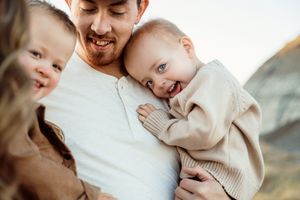 A loving parent holds and embraces their baby in a tender moment against a soft, neutral background.