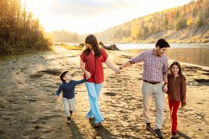 People walking and playing together on a sandy beach at sunset with golden light reflecting off the water.