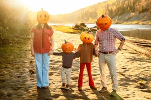 Group of people walking along a beach at sunset with pumpkins and fall decorations for Halloween.
