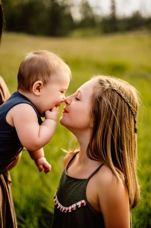 A tender moment between parent and baby in a sunny green field during golden hour.