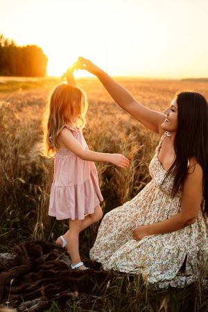 Sweet moment between adult and child playing together in a sunlit wheat field at golden hour.