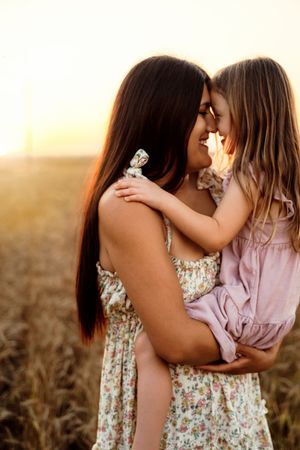An intimate sunset portrait of a tender embrace between parent and child in a wheat field at golden hour.