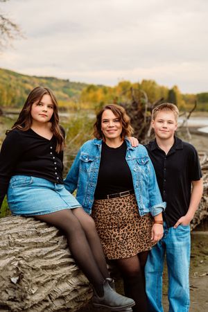 A group in coordinated black and denim outfits poses casually outdoors during an autumn photoshoot.