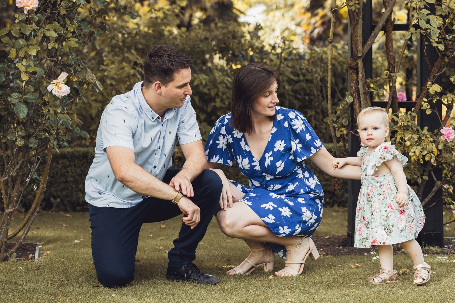 A family spends time together outdoors in a garden setting during a warm day.