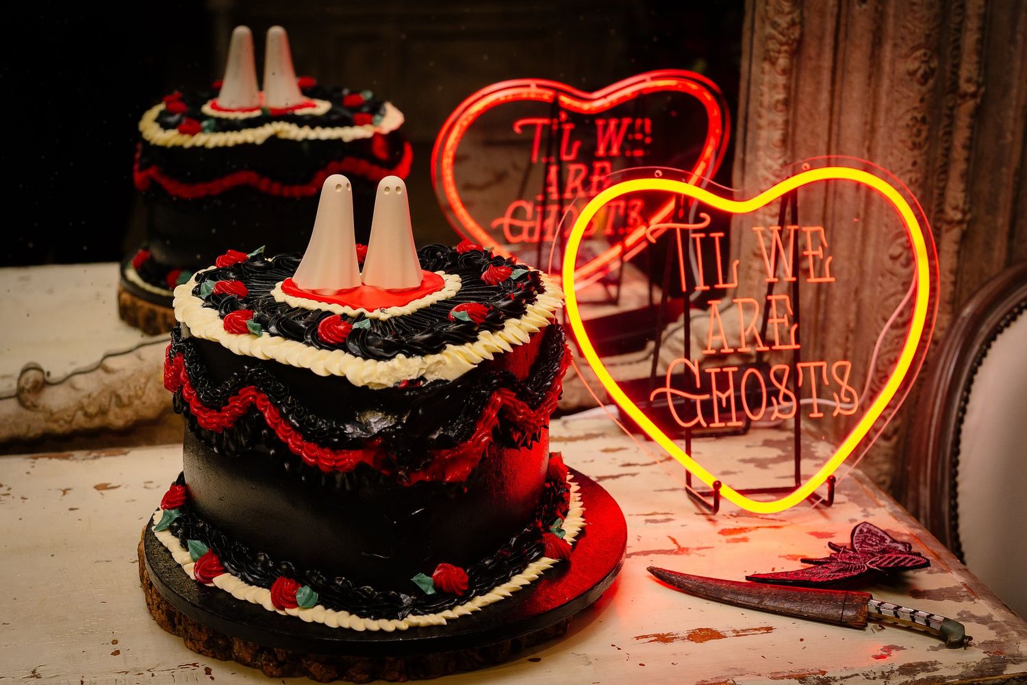 Black heart-shaped Halloween wedding cake by The Cake Lady with ghost cake toppers by York Ghost Merchants and a Til We Are Ghosts neon sign