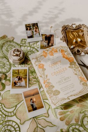 Elegant wedding invitation suite with ornate gold and peach floral designs displayed alongside vintage-style photographs.