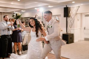 Happy couple dancing together during their wedding reception in an elegant white ballroom.