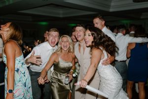 Energetic group of wedding guests laughing and dancing at a lively reception party.