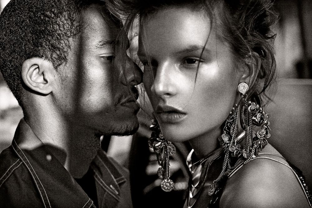 Black and white photo of a man and woman in an intimate close-up, woman wearing ornate statement earrings.