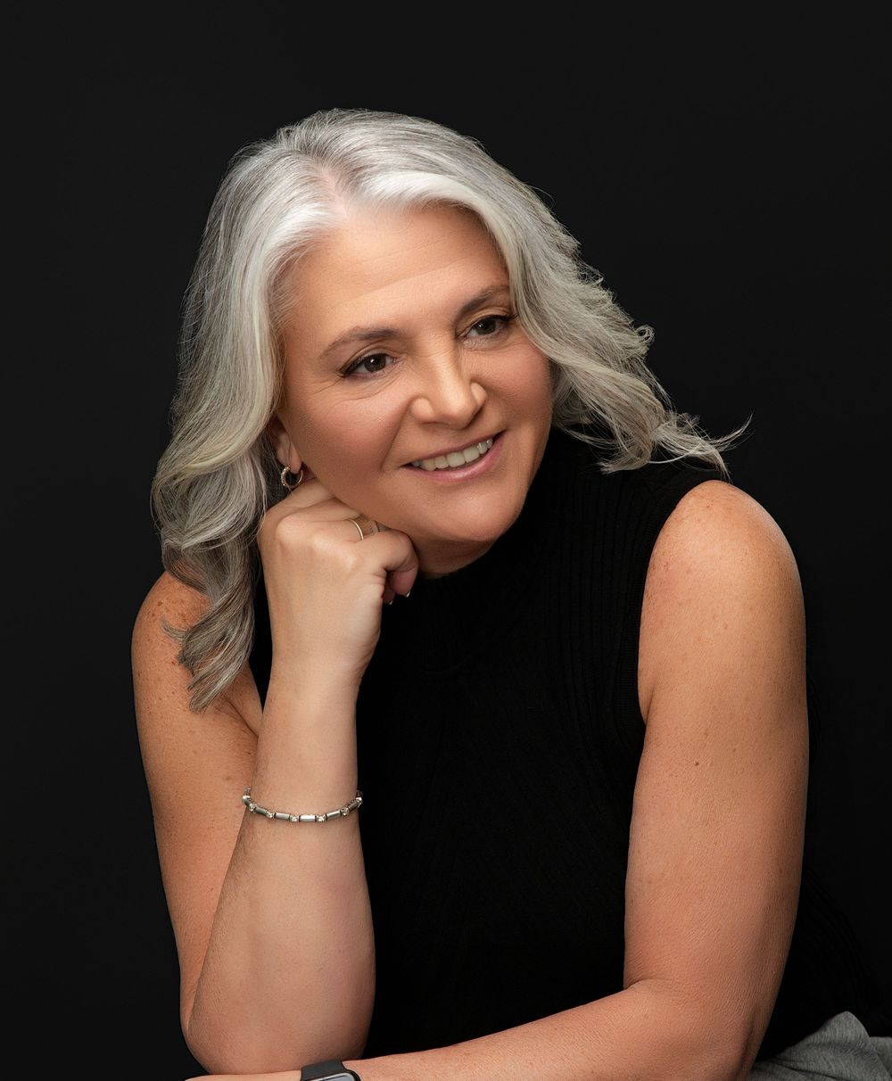 Woman in black with her chin on her hands on a dark backdrop, executive portrait in Sarasota