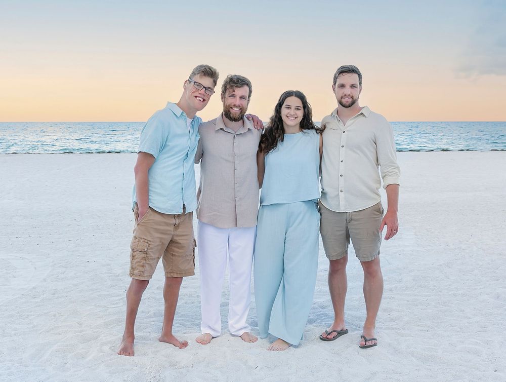 Grown children of the family in coastal pastels on the white sand