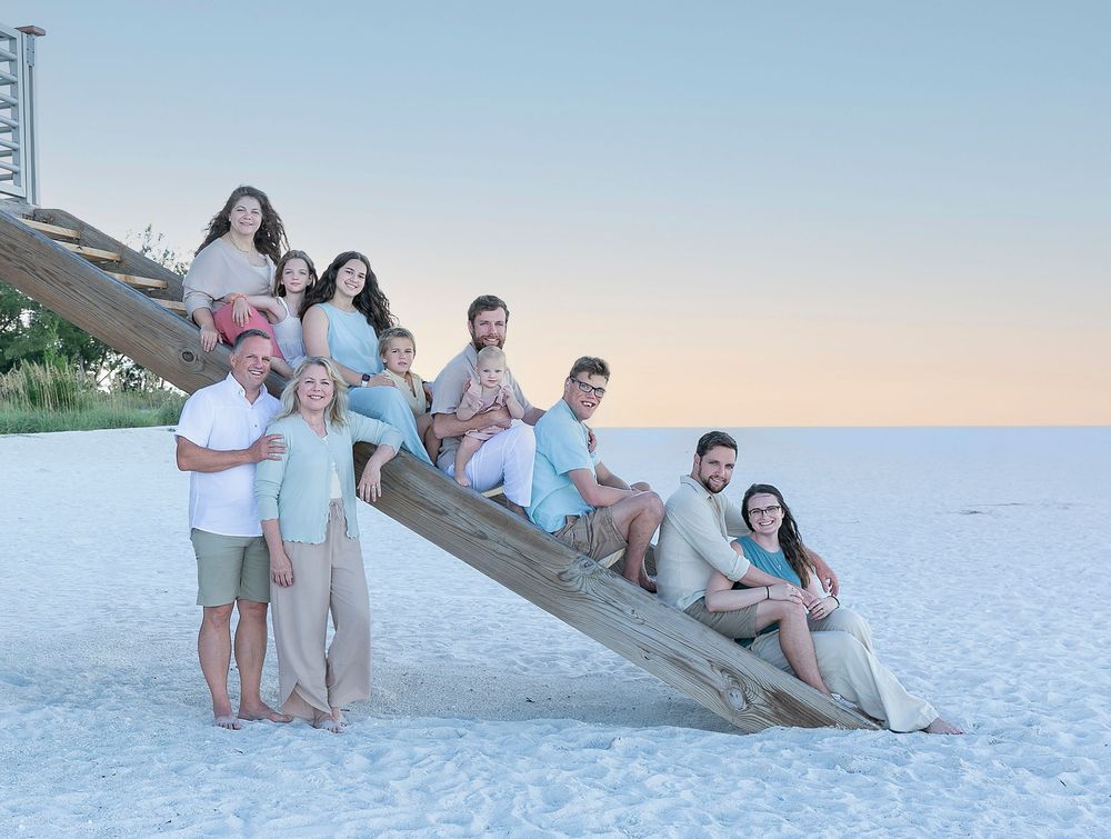 Extended family sitting on wooden beach stairs, playful family reunion photo