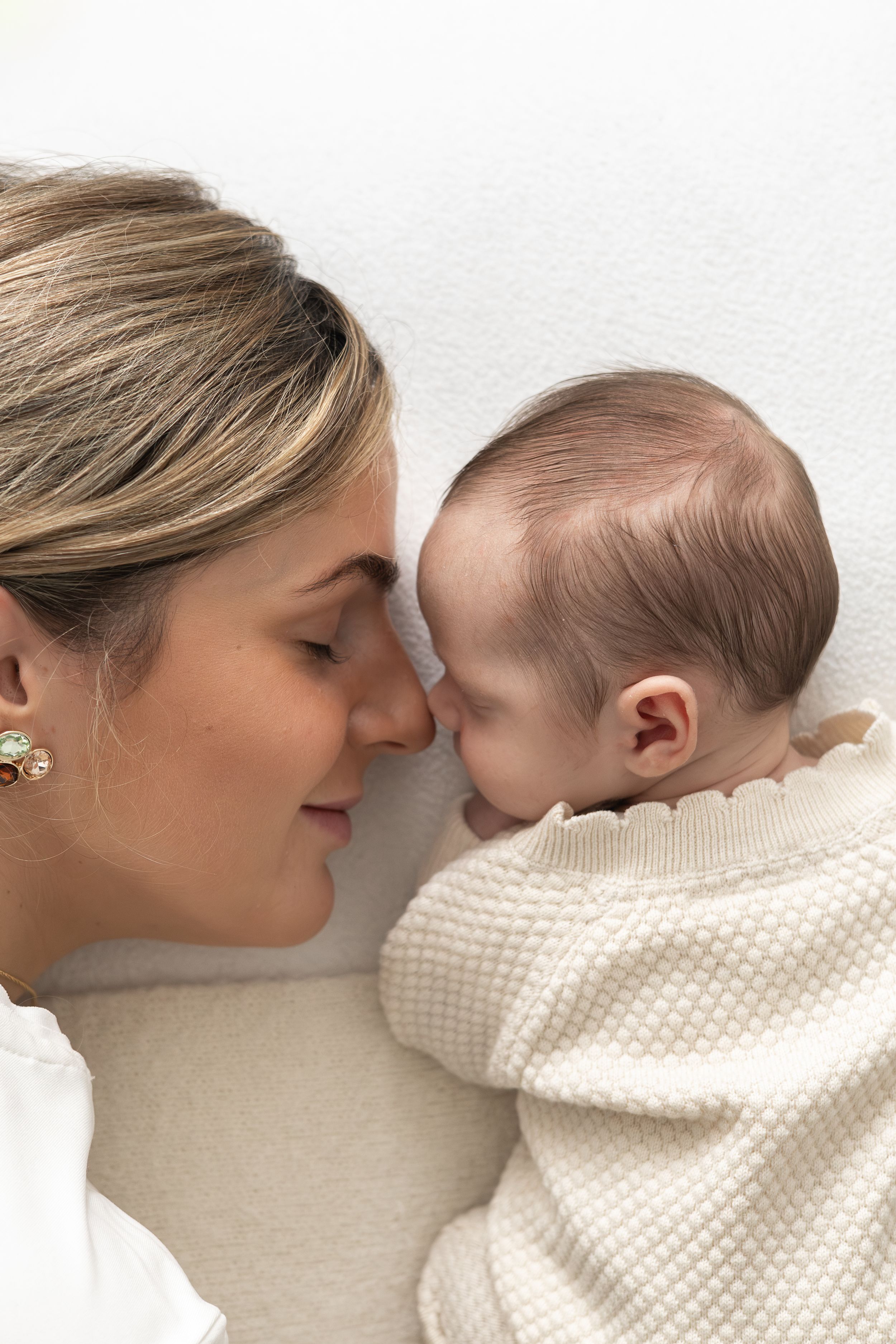 Mother gently cuddling her newborn baby in soft natural light.