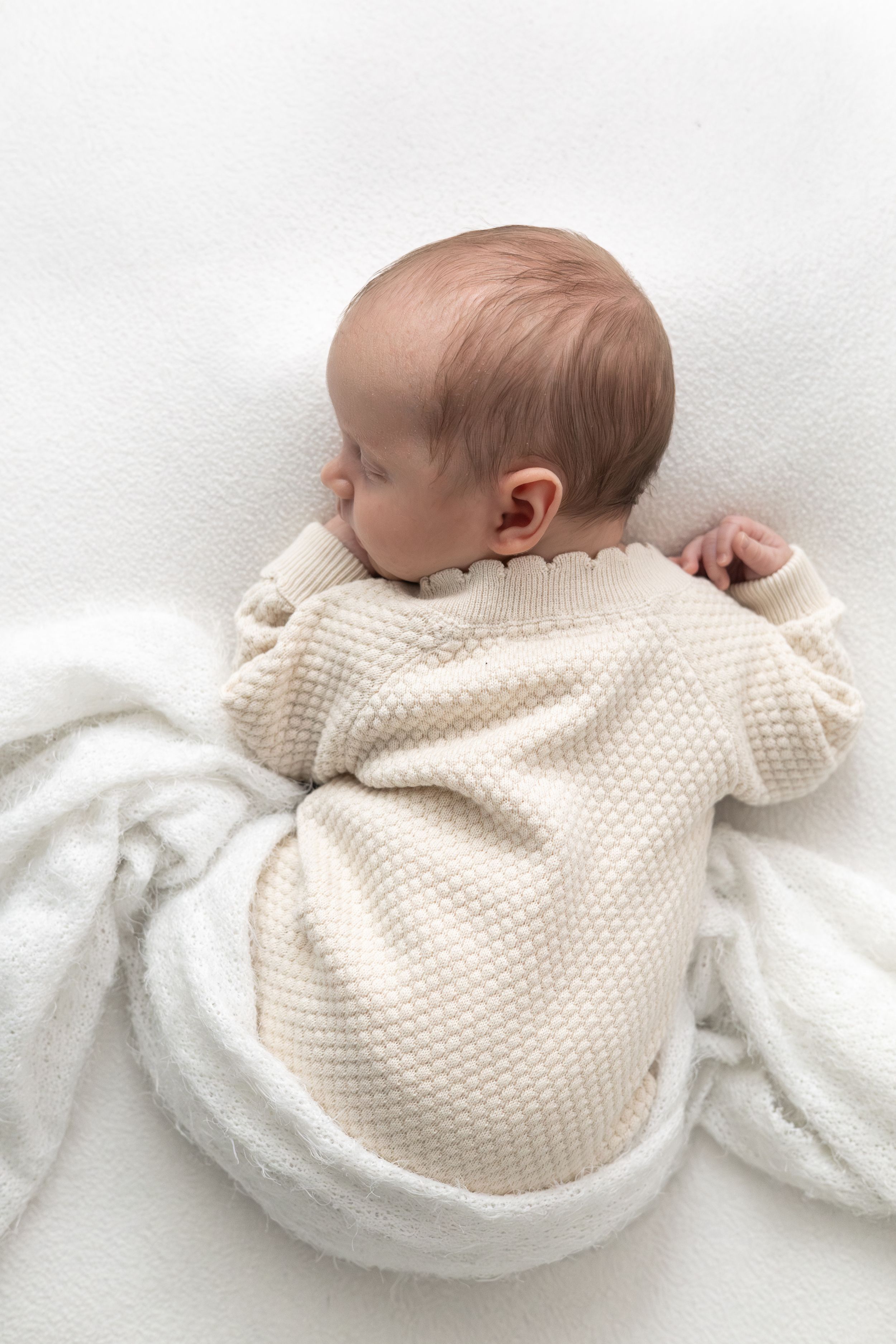 Sleeping newborn wrapped in a soft neutral blanket during a natural newborn photoshoot.