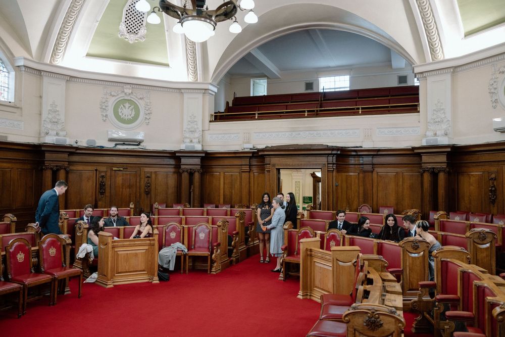 Islington Town Hall chamber room with red seats, wooden panels, arched ceilings, and visitors exploring the elegant interior.
