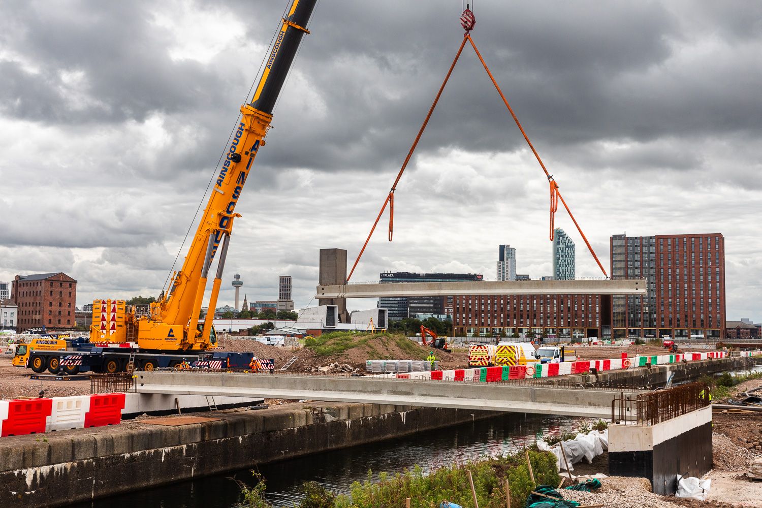 Concrete bridge beam being lifted into place by crane over canal in Liverpool North Dock
