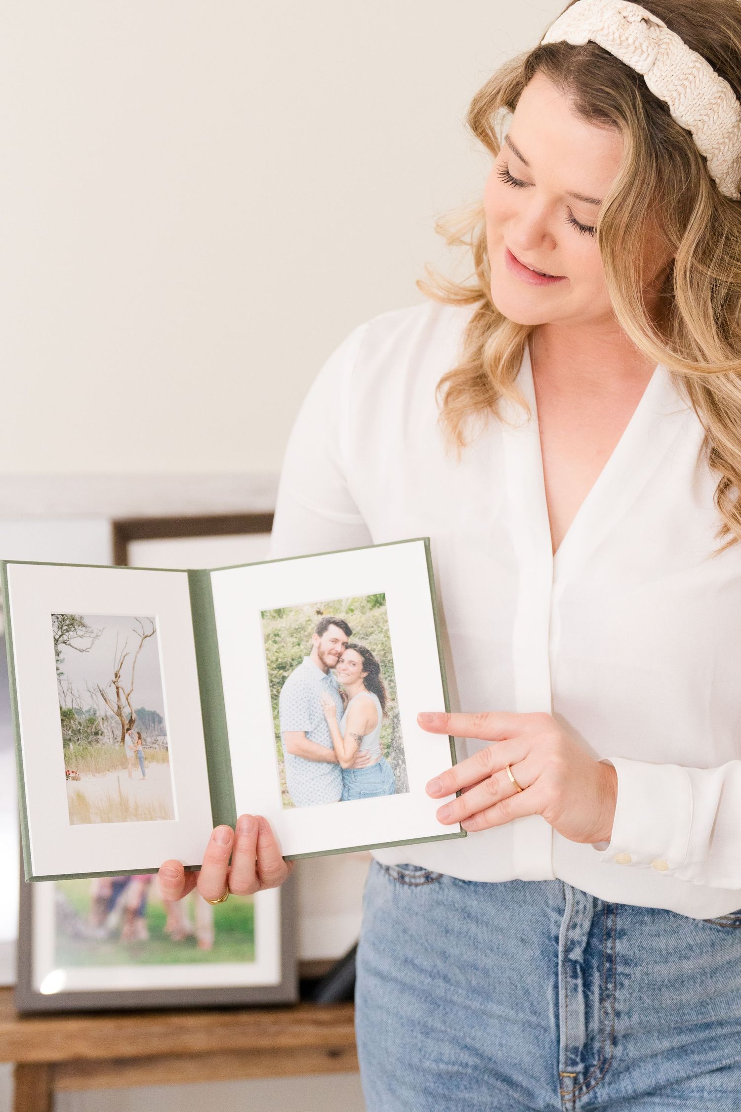 Photographer holding an open matted portrait album, showcasing printed photographs as part of a full service photography experience.