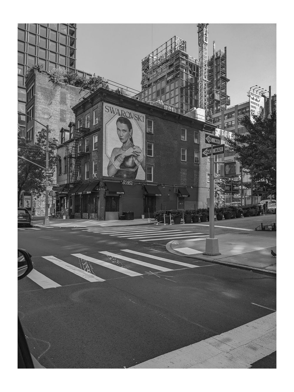 Black and white urban street corner with Swarovski billboard advertisement on brick building in New York City.