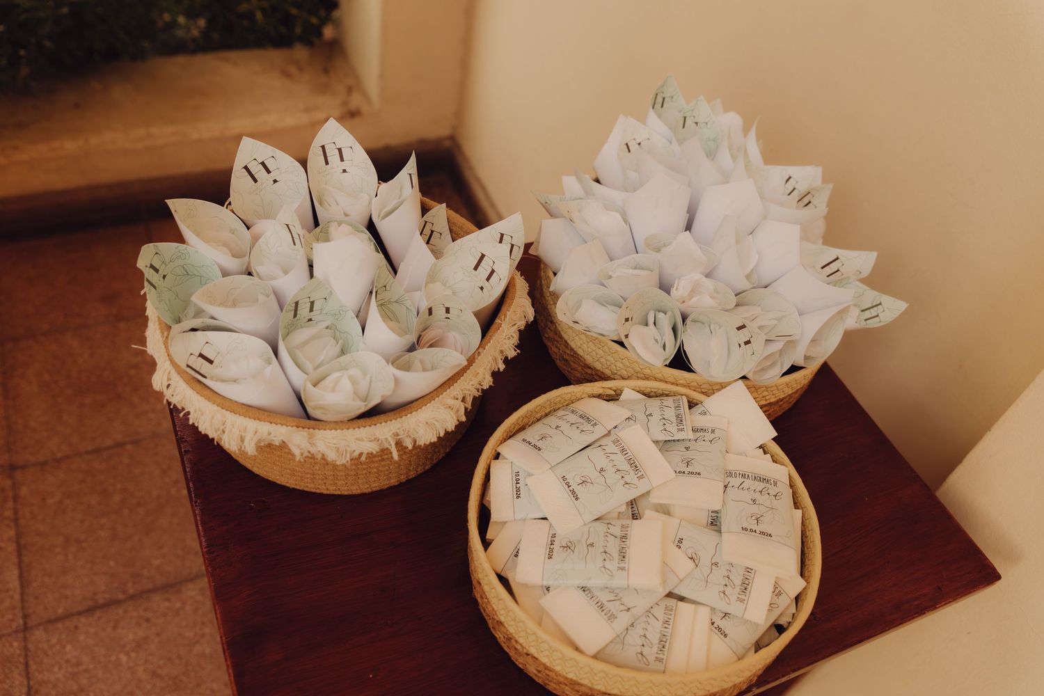 Wicker baskets filled with paper cone wedding favors and seed packets on wooden table.
