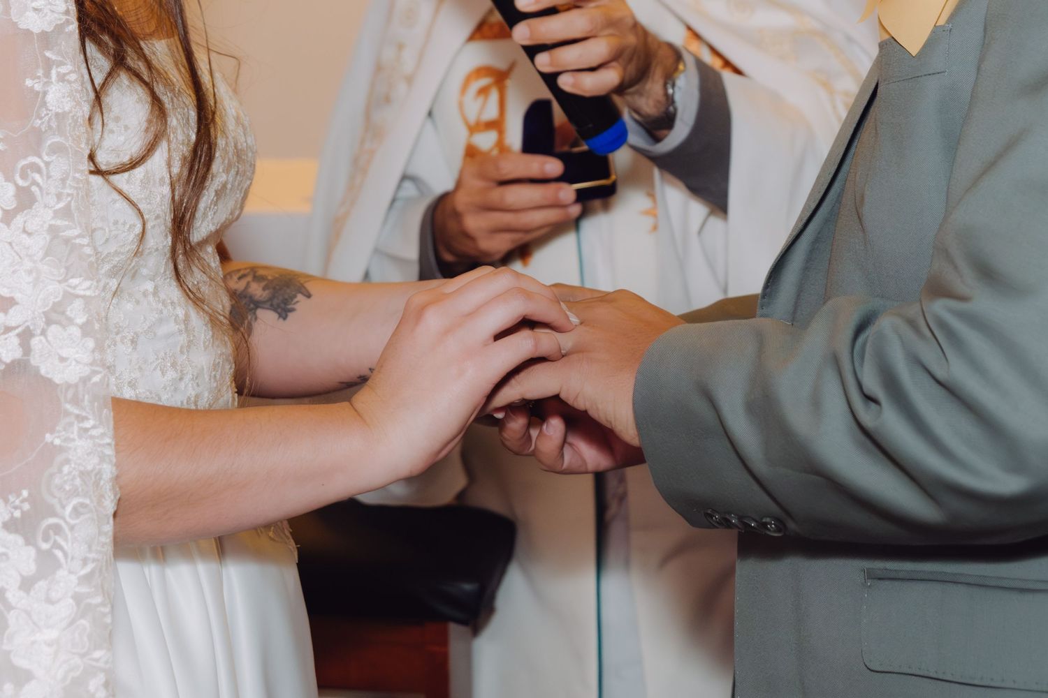 Close-up of bride placing wedding ring on groom's hand during ceremony.