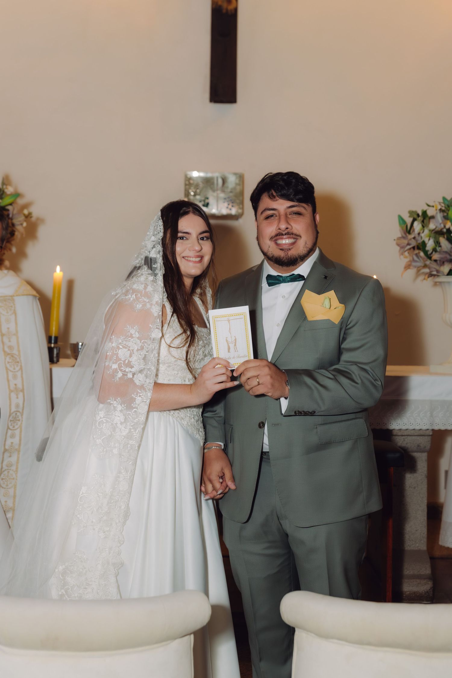 Newlyweds smile and pose together holding marriage certificate inside church.