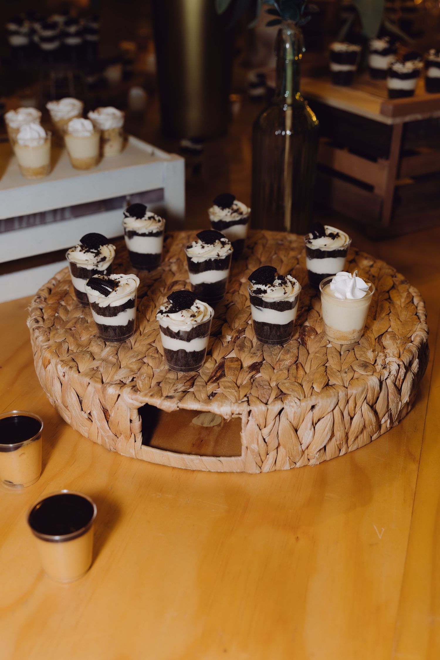 Chocolate and cream layered dessert cups arranged on a round woven tray at a wedding reception.