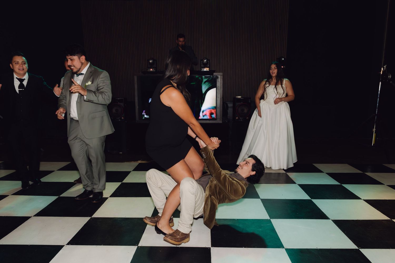 Wedding guests dancing and dipping on a black and white checkered dance floor at reception.