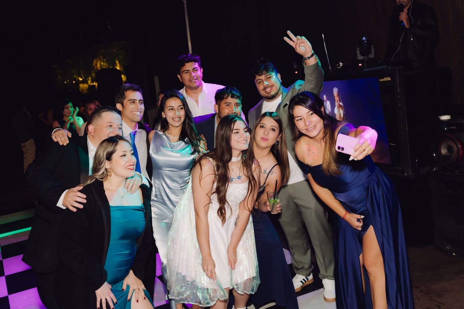 Group of young people posing together and smiling at an outdoor evening formal party event.