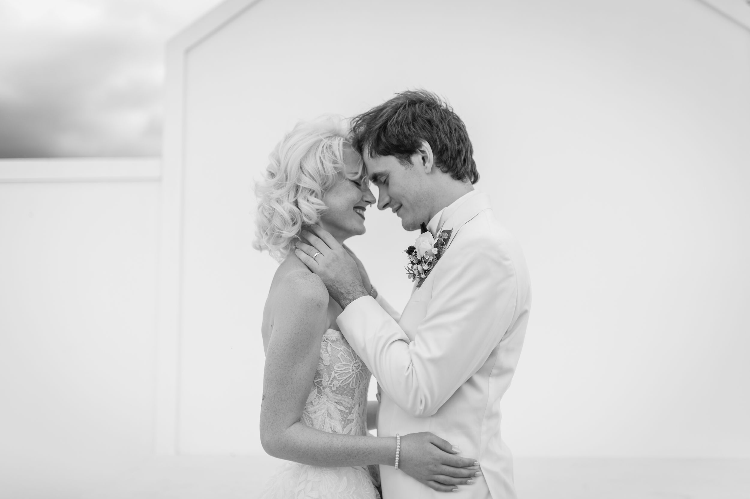 Black and white photo of a bride and groom sharing an intimate moment, touching foreheads at their wedding.