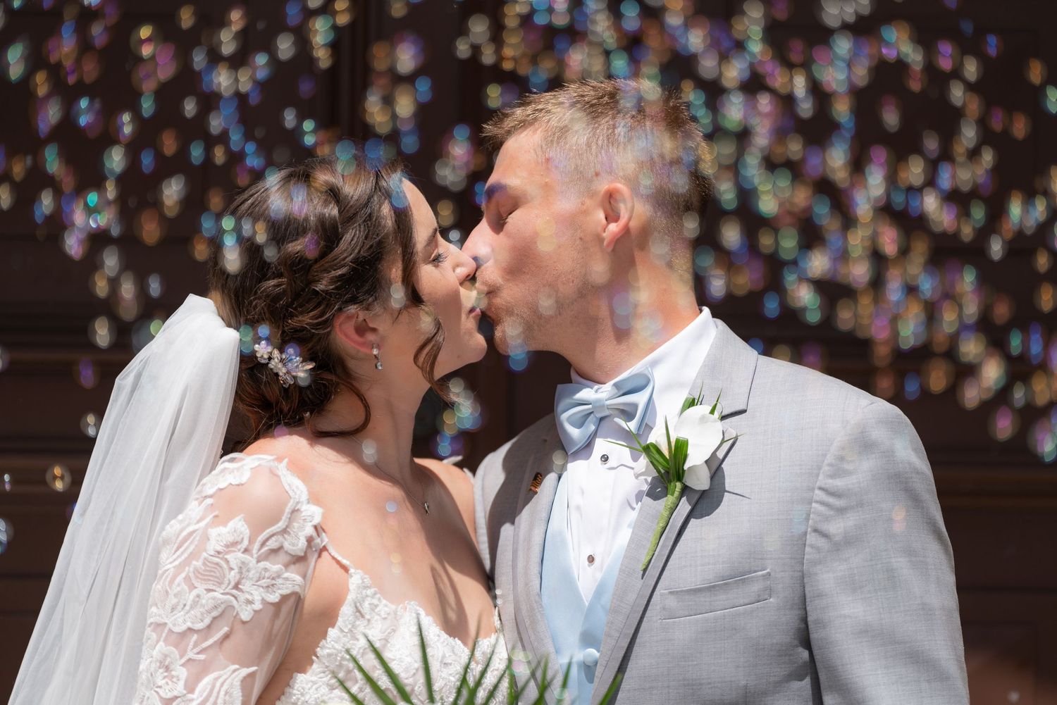 Newlyweds kissing surrounded by bubbles at a wedding at St. Christopher Catholic Church in Hobe Sound, FL