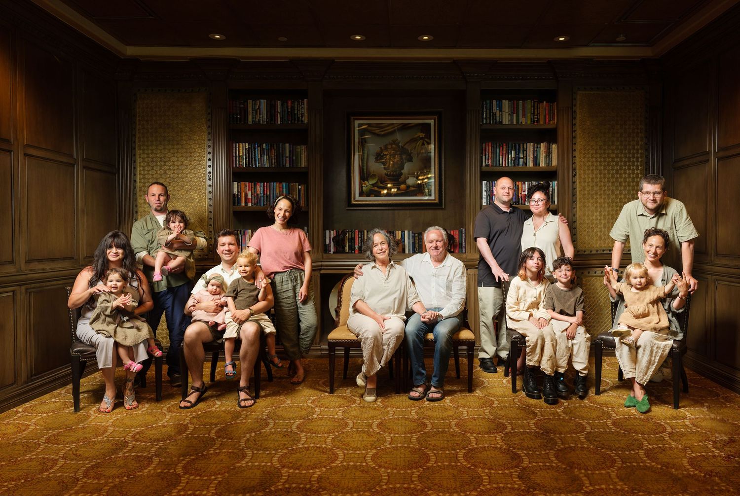 Large multigenerational family portrait posed in an elegant wood-paneled library with bookshelves.