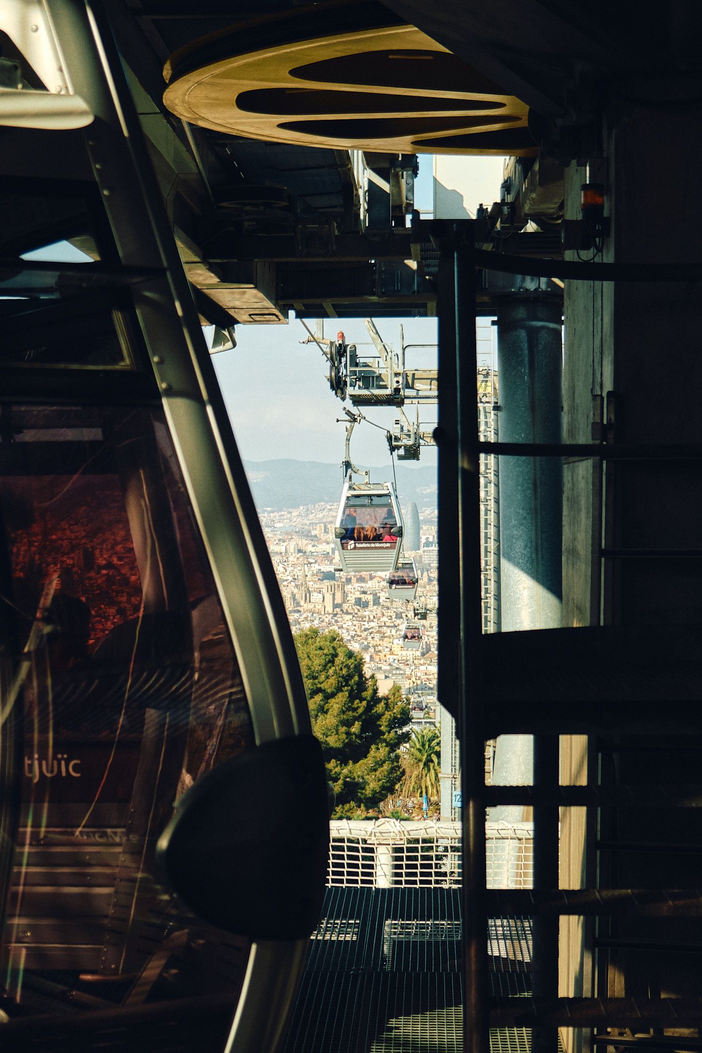 Cable car gondolas descend from a mountain station with panoramic city views visible in the background.