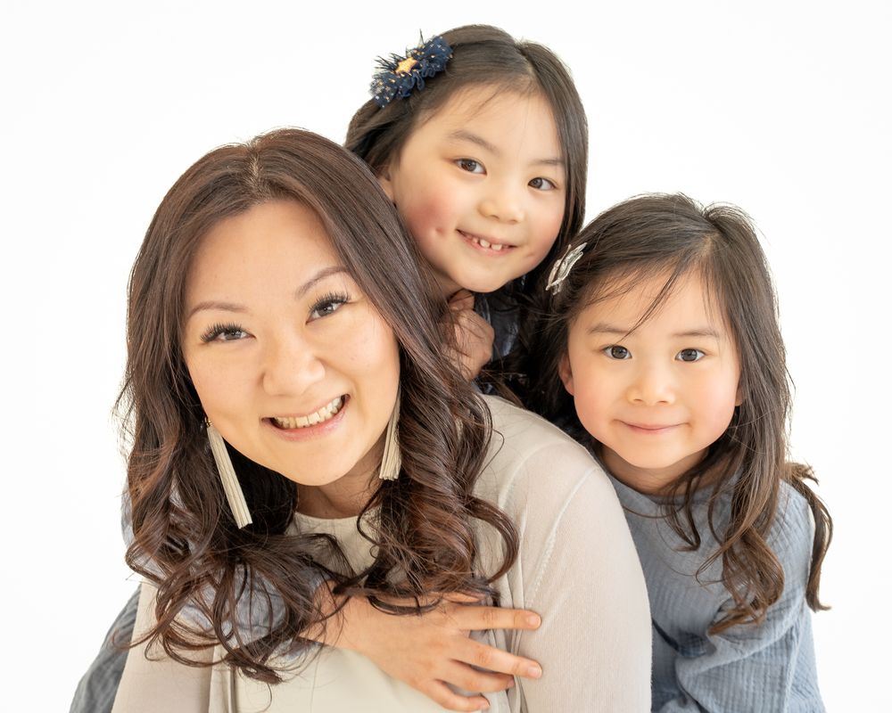 Mother smiling with her two young daughters during a studio portrait session.