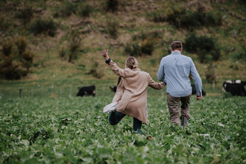 Couple running through an animal stock field on their farm