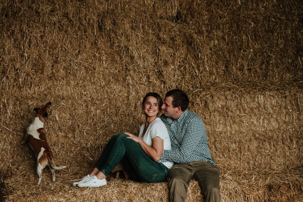 Couple and their dog sitting on haybales on the family farm