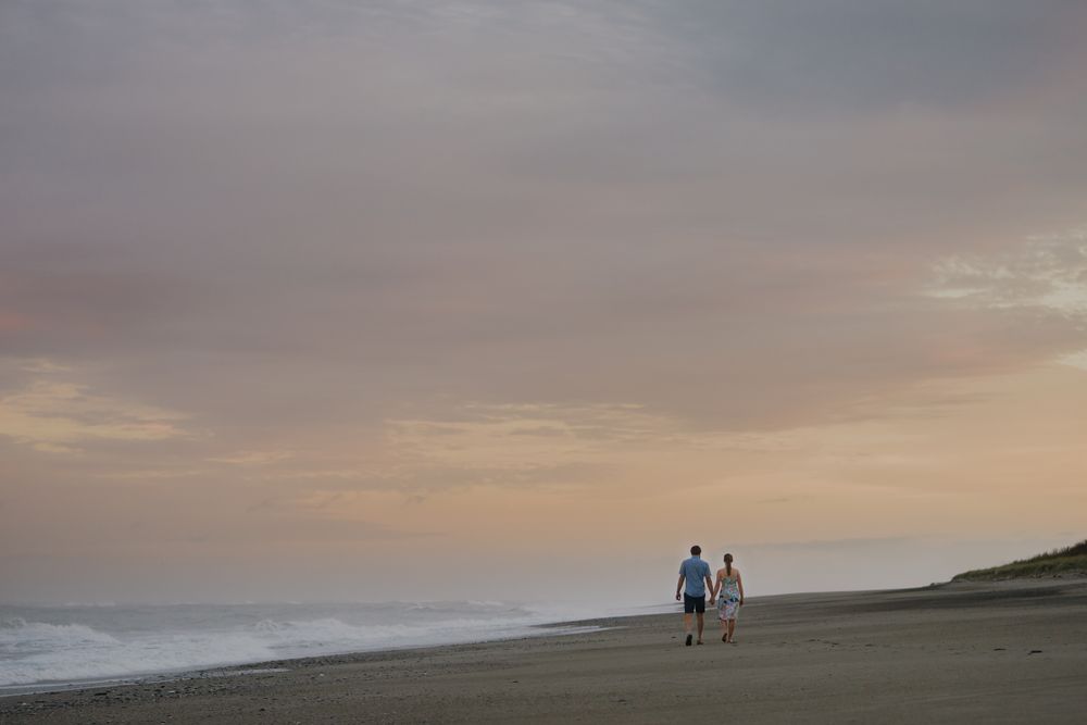 Couple walking on the beach at sunrise on a beach south of Hokitika on the West coast of New Zealand